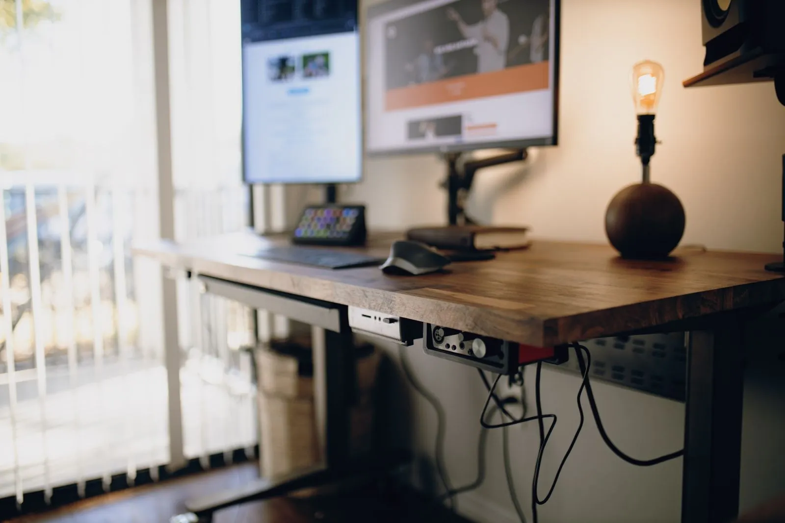 A desk arranged with the screen raised to eye level and the keyboard pulled close